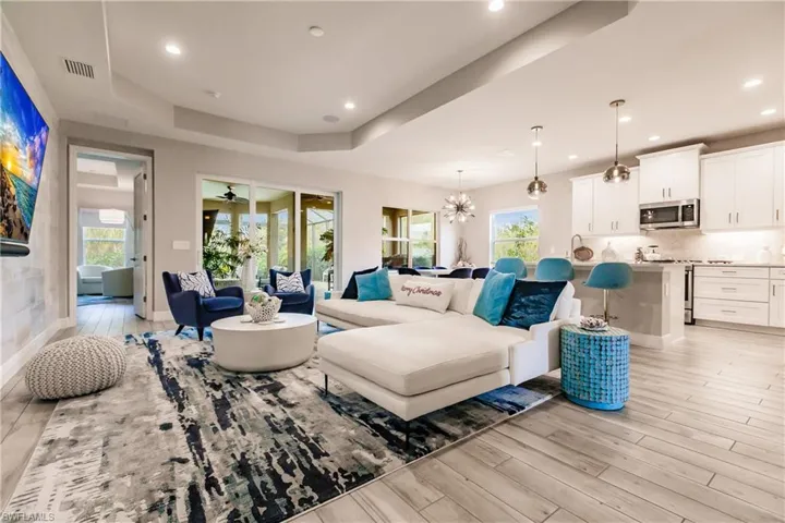Living area featuring a tray ceiling, a chandelier, plenty of natural light, recessed lighting, and light wood-type flooring