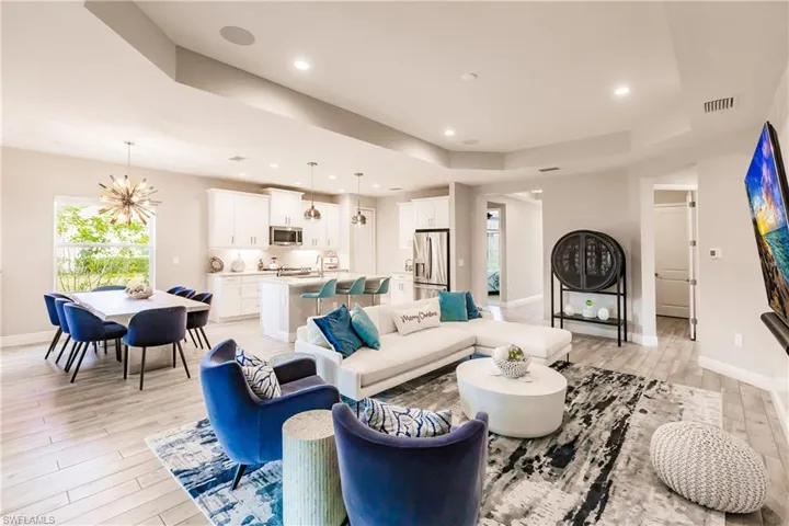 Living area featuring a raised ceiling, recessed lighting, light wood-type flooring, and a chandelier