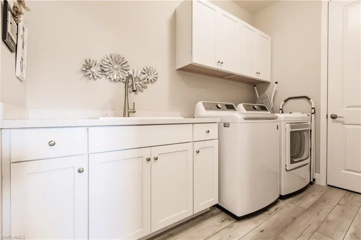 Laundry area with light wood finished floors, cabinet space, and washing machine and clothes dryer