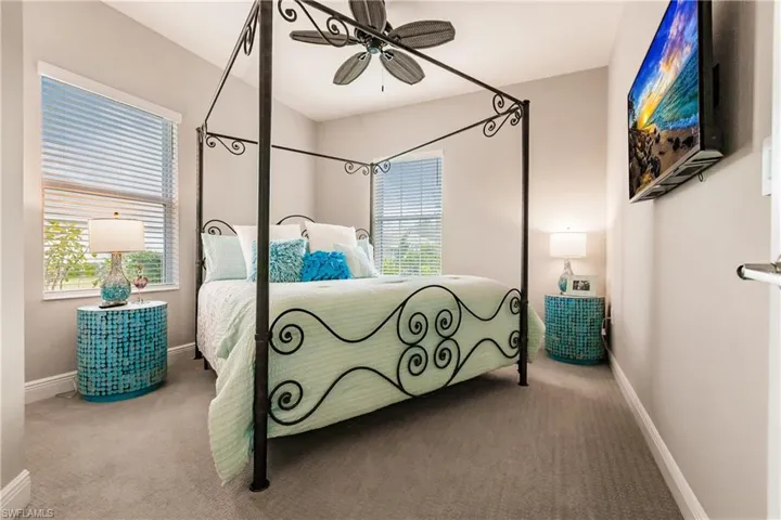 Carpeted bedroom with a ceiling fan and baseboards