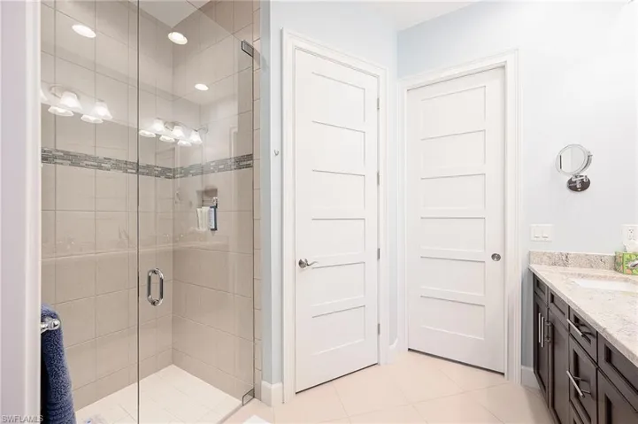 Bathroom with tile patterned flooring, vanity, and a shower with shower door