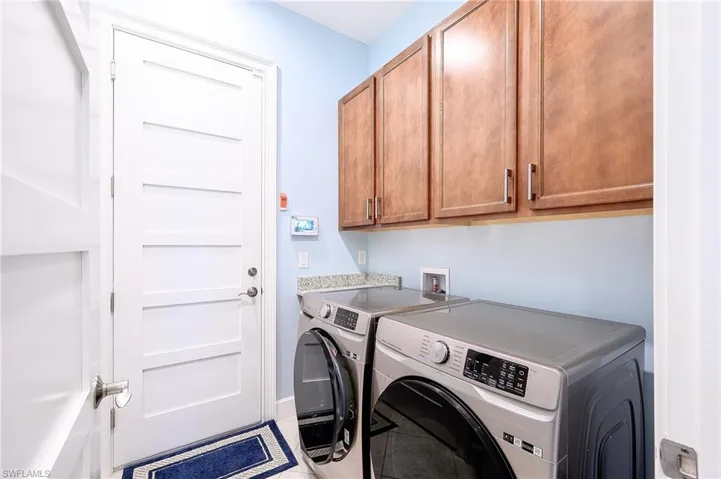 Laundry area with cabinets, washer and clothes dryer, and tile patterned floors