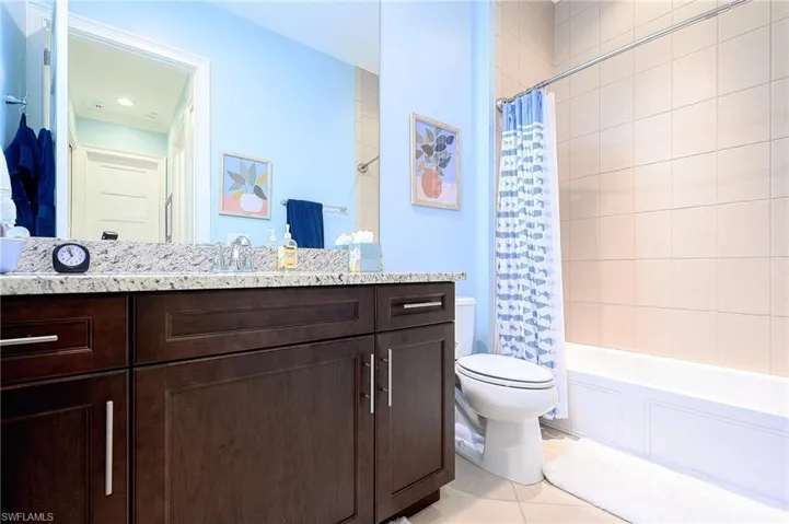 Full bathroom featuring shower / bath combination with curtain, toilet, vanity, and tile patterned floors