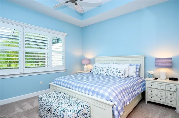 Carpeted bedroom featuring ceiling fan and multiple windows