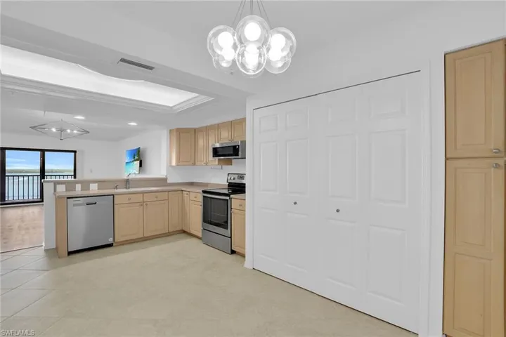 Kitchen with a chandelier, decorative light fixtures, light brown cabinetry, appliances with stainless steel finishes, and recessed lighting