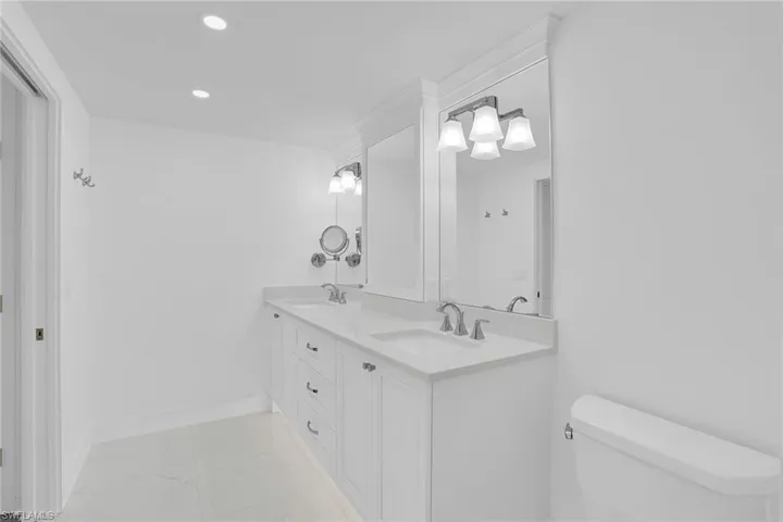Full bath featuring double vanity, recessed lighting, and light marble finish floors