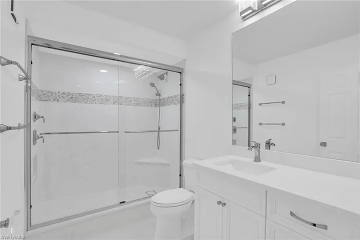 Bathroom featuring vanity and a marble finish shower
