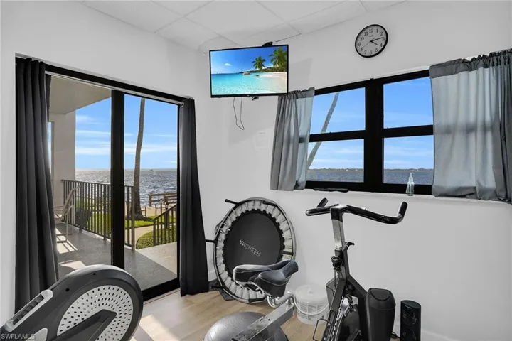 Workout room with light wood-style floors, healthy amount of natural light, and a paneled ceiling