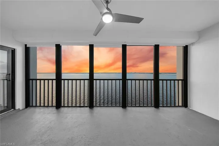 Empty room featuring a water view, ceiling fan, a wall of windows, and finished concrete floors