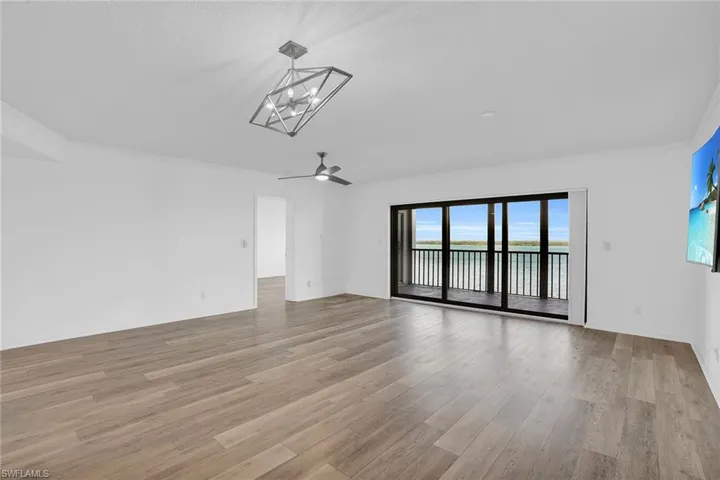 Unfurnished room featuring light wood finished floors, ornamental molding, a water view, and a ceiling fan