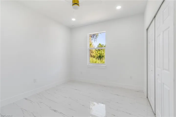 Unfurnished bedroom with recessed lighting, light marble finish floors, a closet, and a ceiling fan