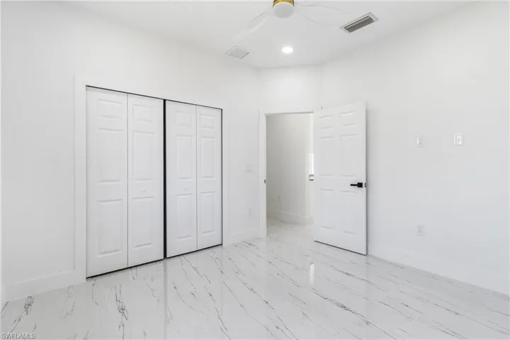 Unfurnished bedroom featuring ceiling fan, a closet, recessed lighting, and light marble finish flooring