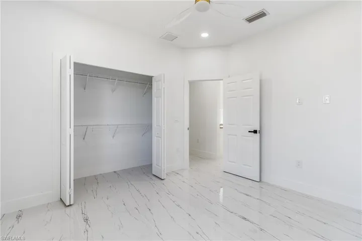 Unfurnished bedroom featuring ceiling fan, a closet, recessed lighting, and light marble finish flooring