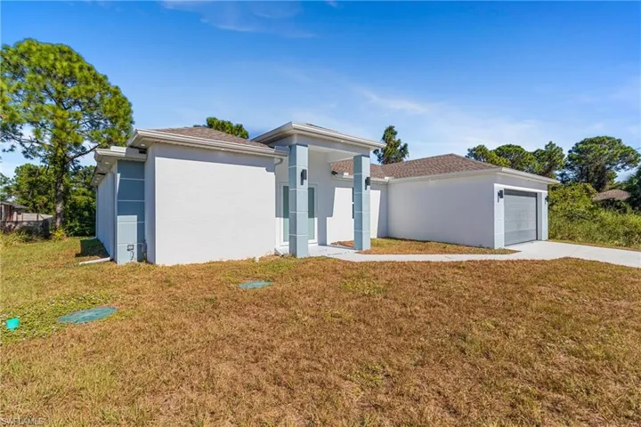 View of front of property featuring a front lawn, stucco siding, a garage, and concrete driveway