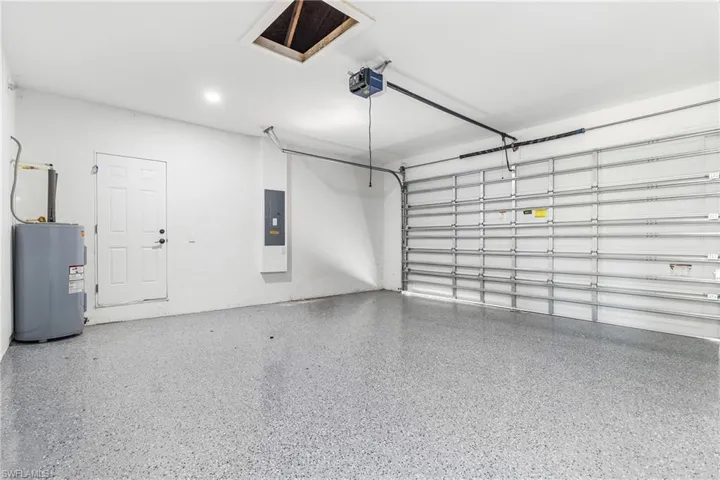 Garage featuring water heater, electric panel, and a garage door opener