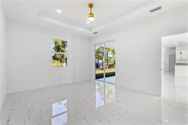Spare room with plenty of natural light, a ceiling fan, recessed lighting, and light marble finish flooring