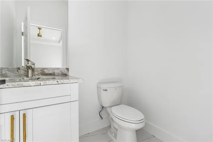 Half bath with vanity and light marble finish flooring