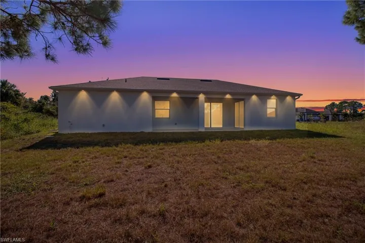 Back of house with a yard, a patio area, and stucco siding