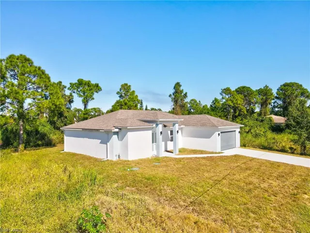 View of front of house featuring a front lawn, concrete driveway, stucco siding, and an attached garage