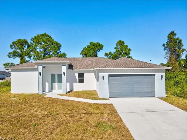 Single story home featuring french doors, stucco siding, a front lawn, driveway, and an attached garage
