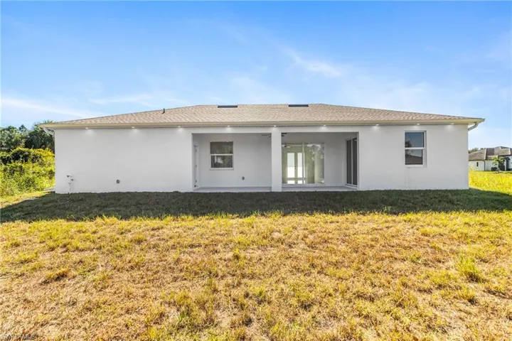 Rear view of property featuring a yard, a patio area, and stucco siding