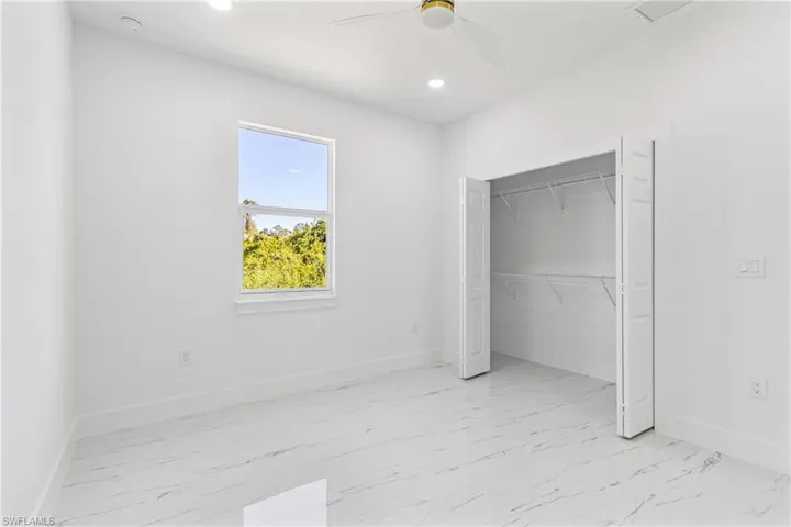 Unfurnished bedroom featuring a ceiling fan, light marble finish flooring, a closet, and recessed lighting