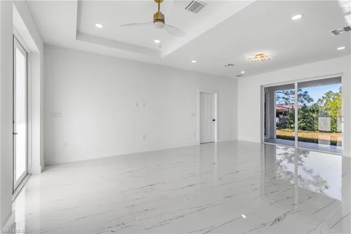 Unfurnished room featuring healthy amount of natural light, recessed lighting, ceiling fan, and light marble finish flooring