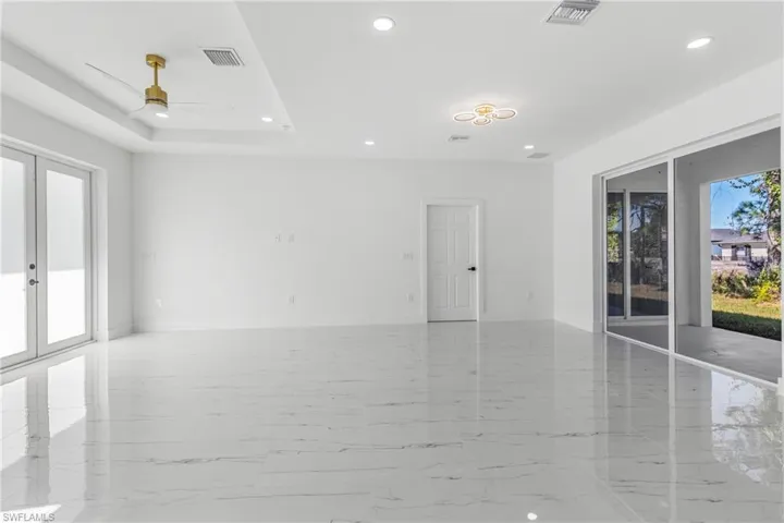 Spare room with healthy amount of natural light, a ceiling fan, french doors, recessed lighting, and light marble finish flooring