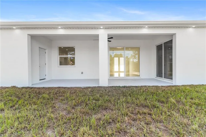 Rear view of house featuring stucco siding, a patio, and a yard