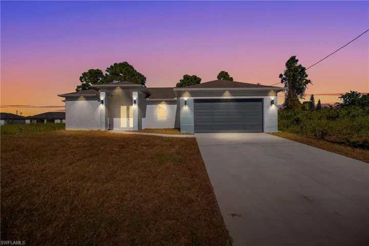 Prairie-style house with stucco siding, driveway, a front lawn, and a garage