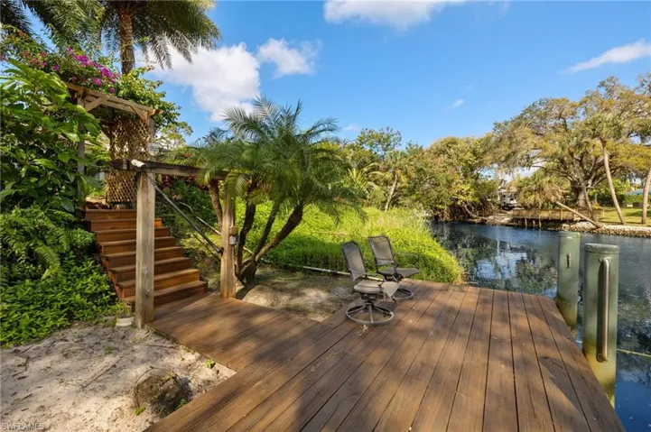 Wooden deck with stairs, a water view, and a boat dock