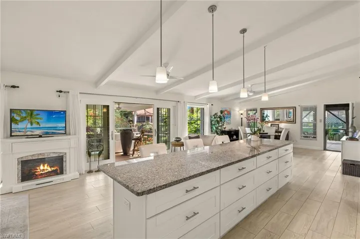 Kitchen with dark stone countertops, open floor plan, white cabinetry, and light wood-style flooring