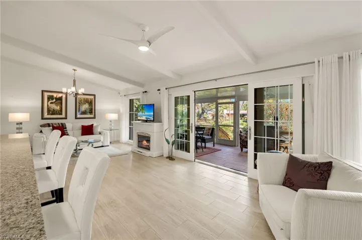 Living room with light wood-type flooring, a warm lit fireplace, a ceiling fan, and a chandelier
