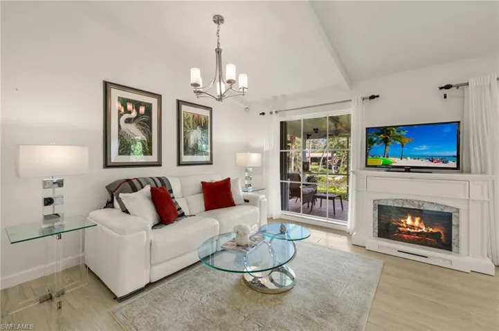 Living room with light wood-style flooring, a chandelier, a premium fireplace, and vaulted ceiling