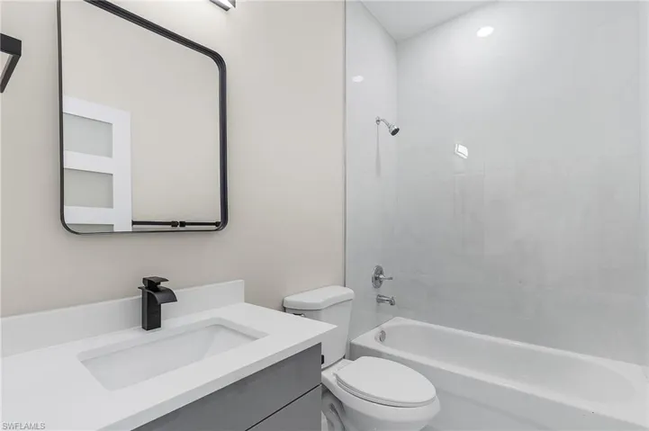 Full bathroom featuring vanity, tiled shower / bath combo, and toilet