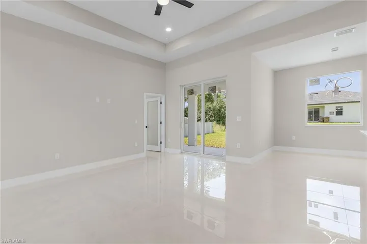 Empty room featuring light tile patterned flooring, a raised ceiling, and ceiling fan