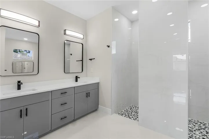 Bathroom with a tile shower, tile patterned floors, and double sink vanity