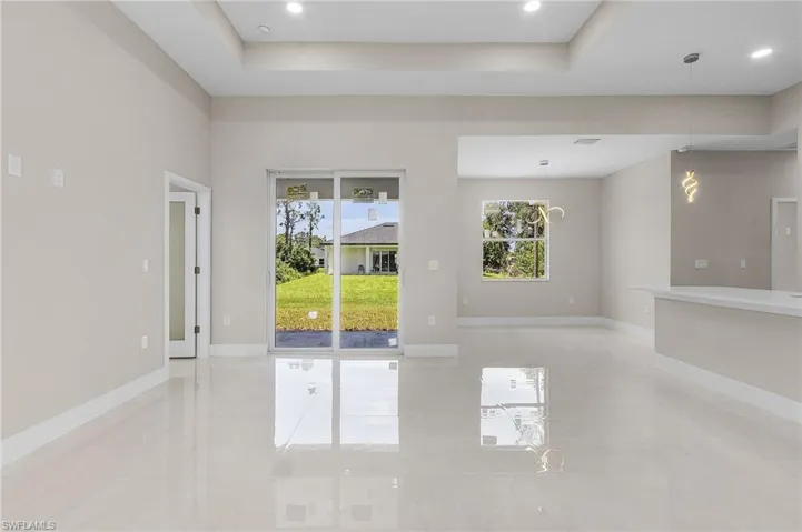 Tiled spare room featuring an inviting chandelier and a tray ceiling