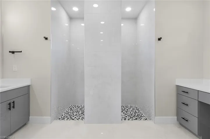 Bathroom featuring tiled shower, vanity, and tile patterned floors