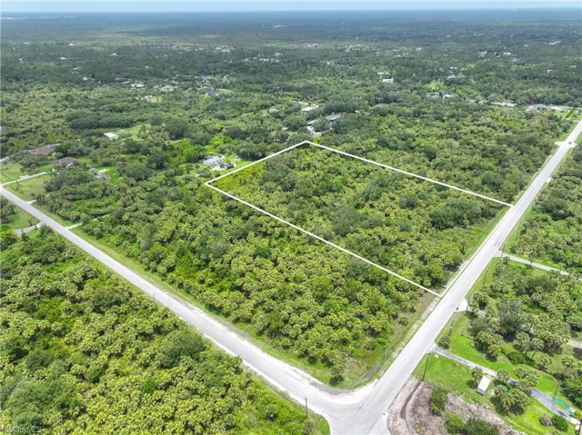 Aerial overview of property's location featuring property parcel outlined and a heavily wooded area