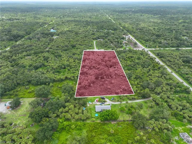 Aerial view of property and surrounding area featuring a heavily wooded area and property parcel outlined