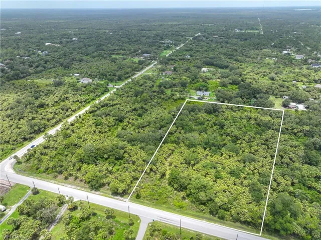 Aerial view of property and surrounding area with a forest and property parcel outlined
