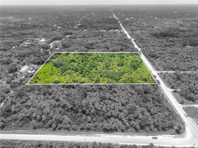 Aerial view of property and surrounding area featuring property boundaries highlighted and a heavily wooded area