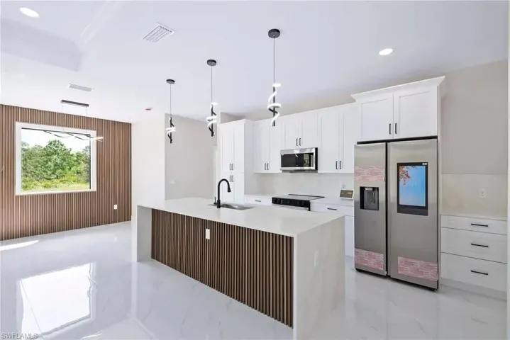 Kitchen featuring wood walls, stainless steel appliances, white cabinetry, light stone countertops, and light marble finish flooring