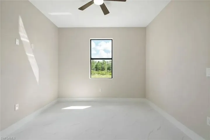 Unfurnished room featuring light marble finish flooring and ceiling fan