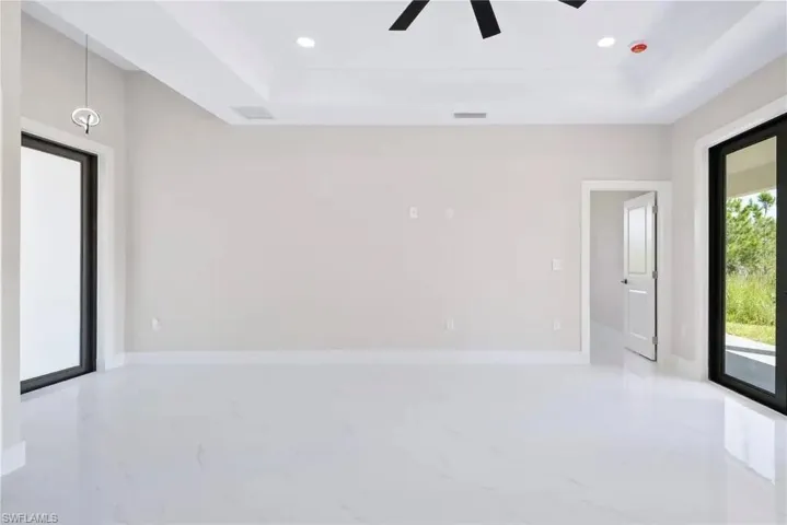 Unfurnished room featuring a tray ceiling, recessed lighting, light marble finish floors, and ceiling fan
