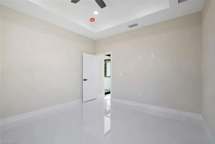 Spare room with a raised ceiling, ceiling fan, light marble finish flooring, and recessed lighting