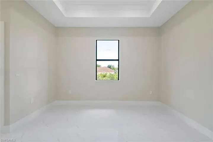 Unfurnished room featuring a tray ceiling and light marble finish floors