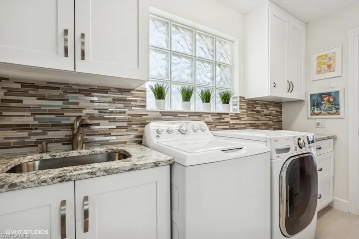 Laundry area featuring sink, cabinets, and independent washer and dryer