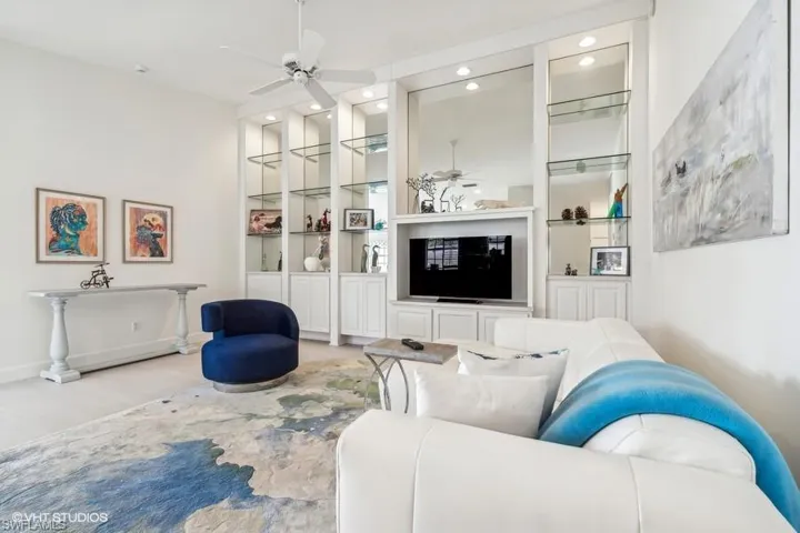 Living room with light hardwood / wood-style flooring, ceiling fan, and built in features